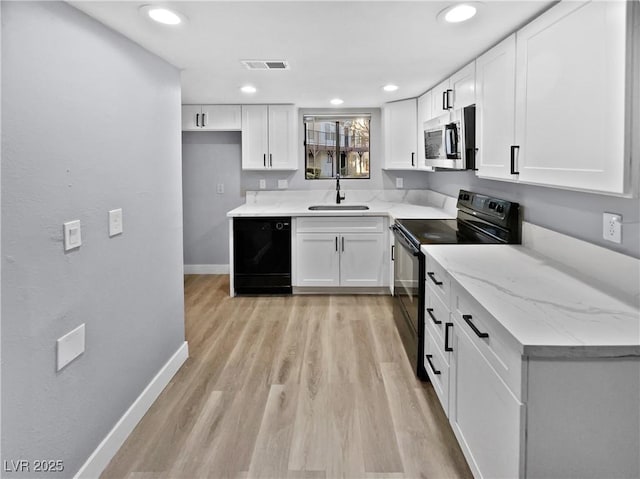 kitchen with black appliances, sink, white cabinetry, light hardwood / wood-style flooring, and light stone counters