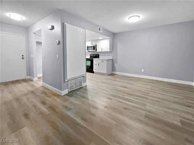 kitchen featuring light hardwood / wood-style flooring, white cabinets, and black / electric stove