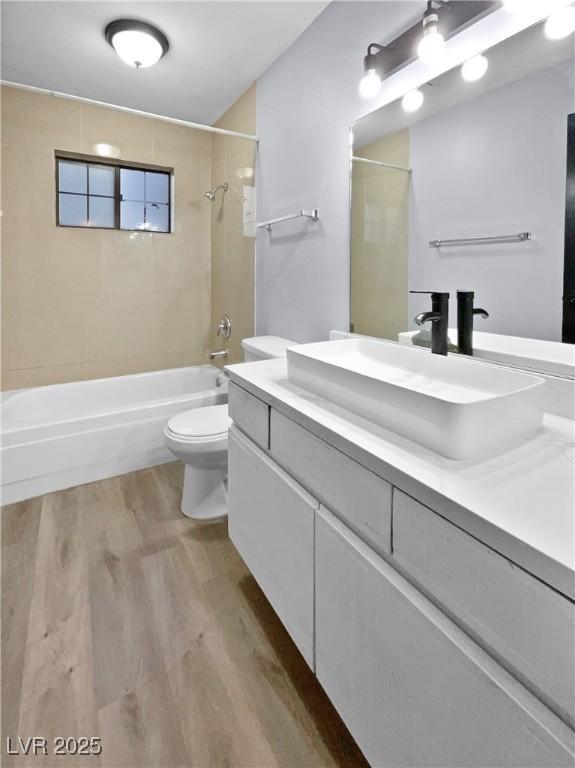 full bathroom featuring toilet, tiled shower / bath, vanity, and hardwood / wood-style floors