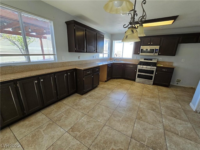 kitchen with hanging light fixtures, a wealth of natural light, sink, and appliances with stainless steel finishes