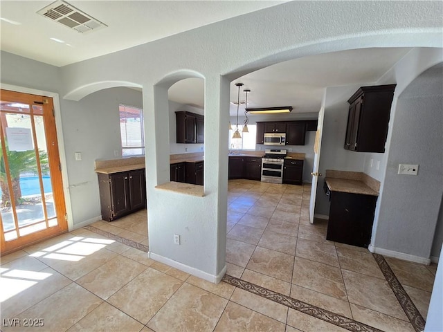 kitchen with light tile patterned floors, stainless steel appliances, and dark brown cabinetry