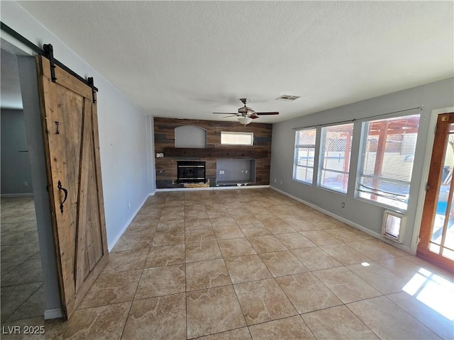 unfurnished living room featuring ceiling fan, a large fireplace, a textured ceiling, and light tile patterned flooring