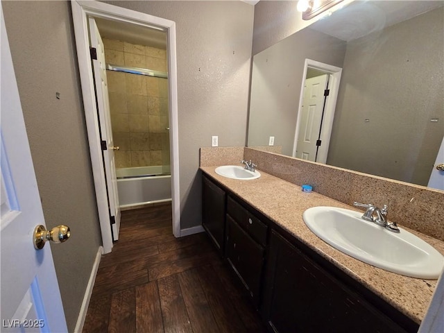 bathroom featuring combined bath / shower with glass door, hardwood / wood-style floors, and vanity