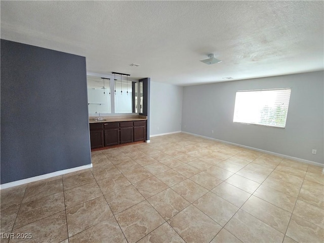 tiled empty room featuring sink and a textured ceiling