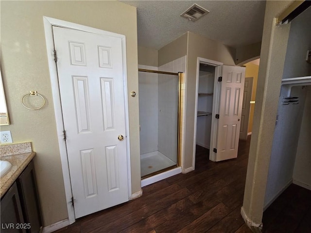 bathroom with hardwood / wood-style flooring, a textured ceiling, an enclosed shower, and vanity