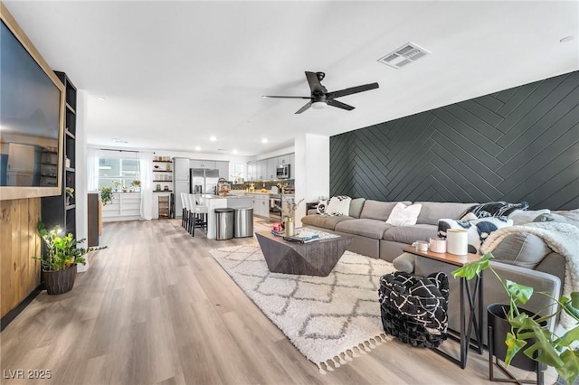 living room with light hardwood / wood-style floors and ceiling fan