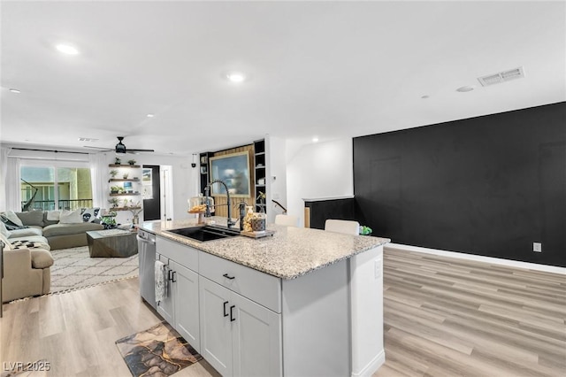 kitchen featuring light hardwood / wood-style floors, ceiling fan, a kitchen island with sink, white cabinets, and sink