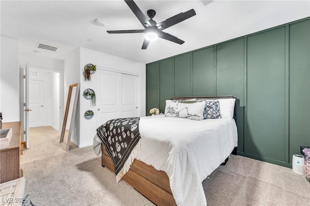 carpeted bedroom with ceiling fan and a closet