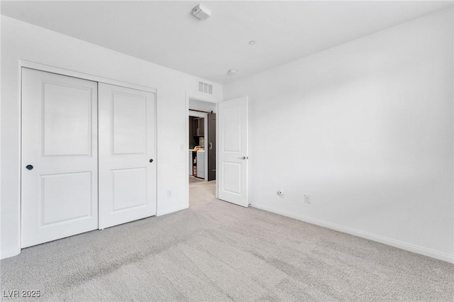 unfurnished bedroom with light carpet and a closet