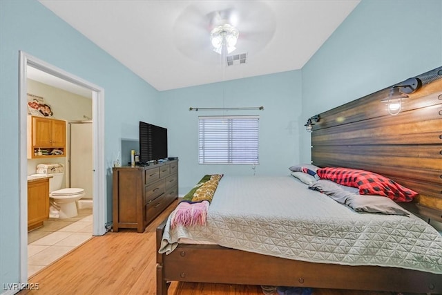 bedroom featuring ceiling fan, ensuite bath, vaulted ceiling, and light hardwood / wood-style floors