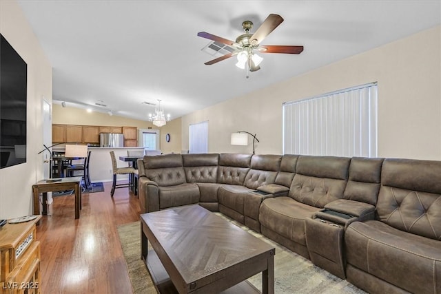 living room featuring ceiling fan with notable chandelier, hardwood / wood-style floors, and vaulted ceiling