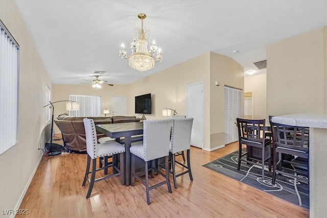 dining room featuring lofted ceiling, ceiling fan with notable chandelier, and light hardwood / wood-style flooring