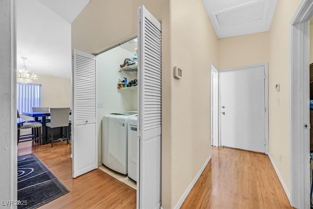 washroom featuring washer / clothes dryer, an inviting chandelier, and hardwood / wood-style floors