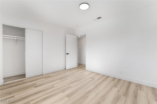 unfurnished bedroom featuring light wood-type flooring and a closet