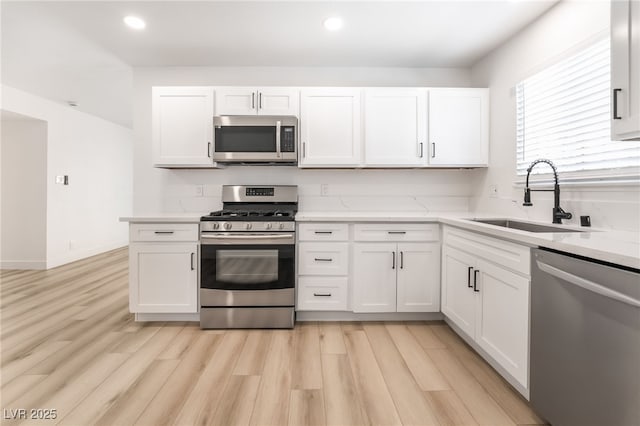 kitchen with stainless steel appliances, white cabinetry, and sink