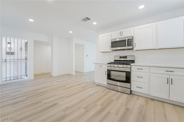 kitchen with white cabinetry, appliances with stainless steel finishes, and light hardwood / wood-style flooring