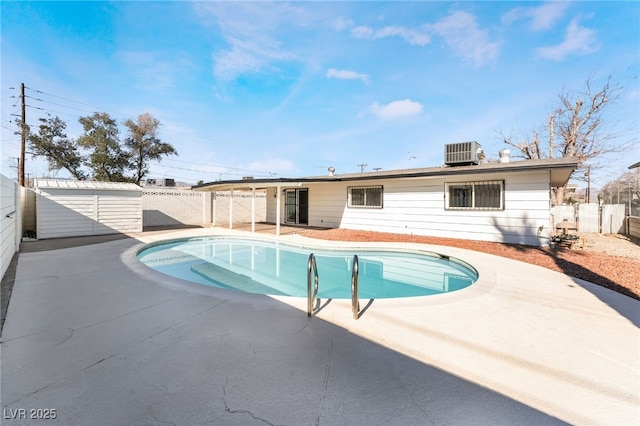 view of swimming pool featuring a patio area, cooling unit, and a storage unit