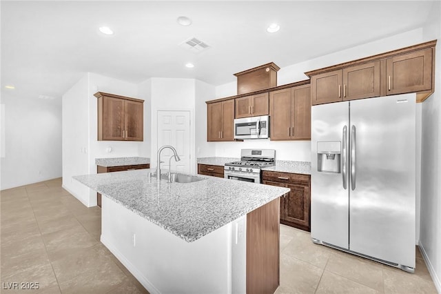 5640 Akula Bay St, North Las Vegas, NV 89081 - kitchen featuring stainless steel appliances, a sink, light tile patterned flooring, a kitchen island with sink, and light stone countertops