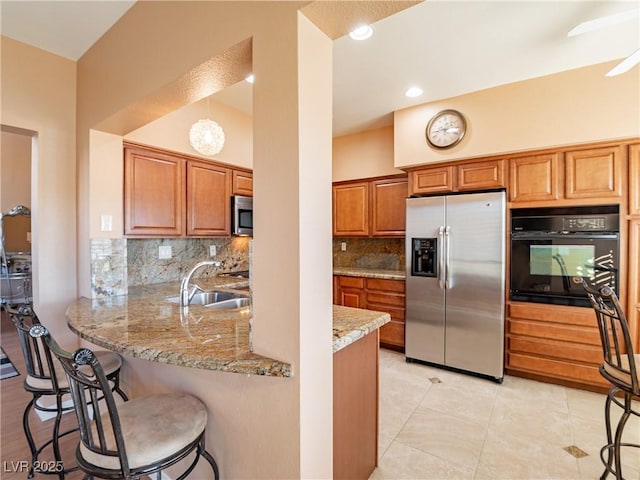 kitchen featuring kitchen peninsula, appliances with stainless steel finishes, backsplash, a kitchen breakfast bar, and sink