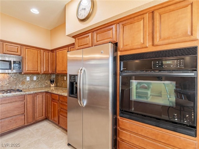 kitchen featuring light tile patterned floors, appliances with stainless steel finishes, tasteful backsplash, and light stone counters