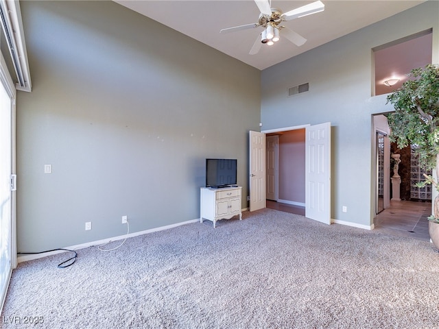 unfurnished bedroom featuring ceiling fan, light carpet, and a high ceiling