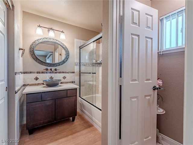 bathroom featuring bath / shower combo with glass door, wood-type flooring, and vanity