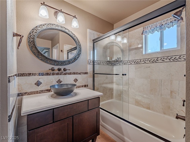 bathroom featuring tile walls, shower / bath combination with glass door, and vanity