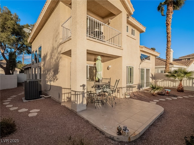 rear view of property with central AC unit, a balcony, and a patio