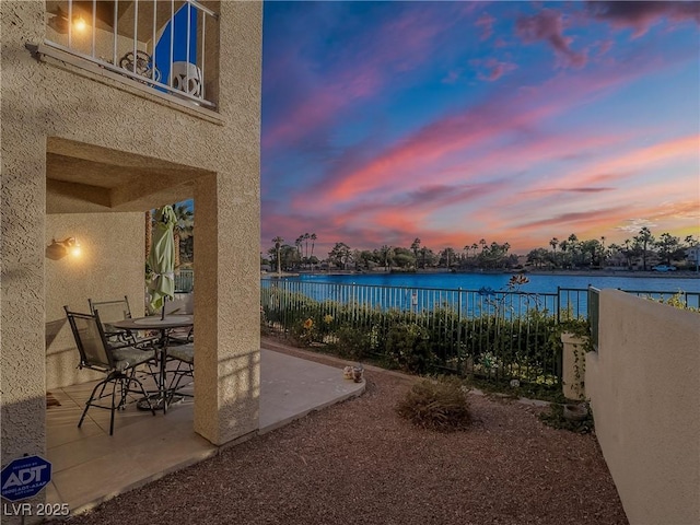 patio terrace at dusk featuring a water view