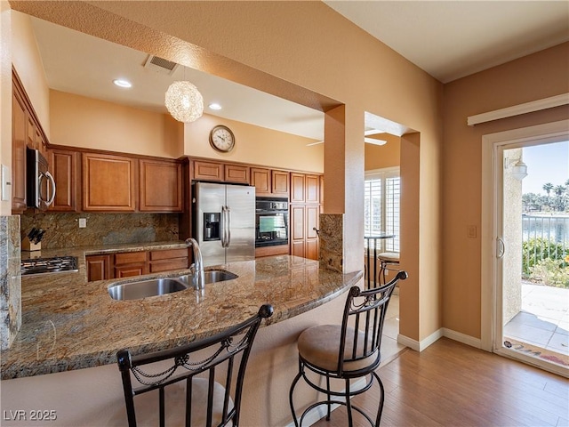 kitchen with kitchen peninsula, stainless steel appliances, backsplash, pendant lighting, and sink