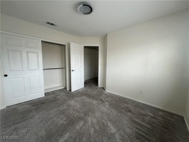 unfurnished bedroom with a closet and dark carpet