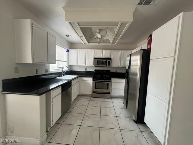 kitchen with decorative light fixtures, sink, stainless steel appliances, and white cabinetry