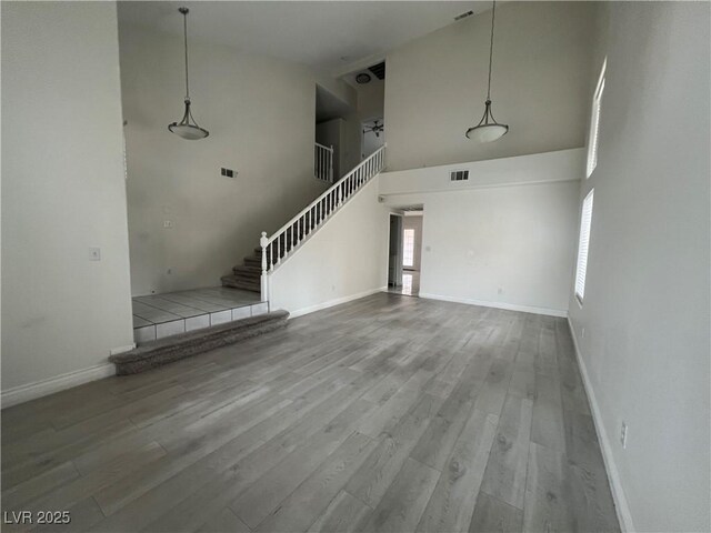 unfurnished living room with hardwood / wood-style floors and a towering ceiling