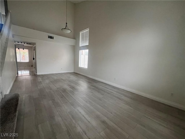 spare room featuring hardwood / wood-style flooring, a high ceiling, and a healthy amount of sunlight