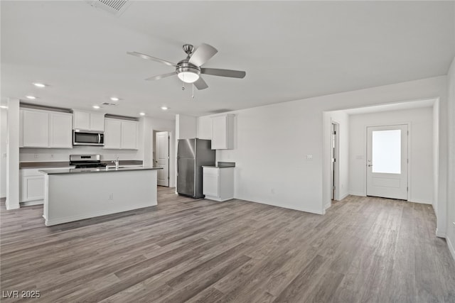 kitchen featuring ceiling fan, light hardwood / wood-style flooring, a kitchen island with sink, appliances with stainless steel finishes, and white cabinets