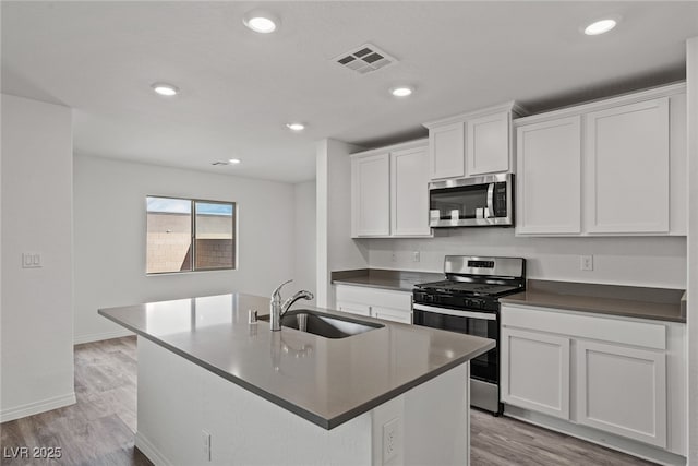 kitchen featuring sink, white cabinets, appliances with stainless steel finishes, and a center island with sink