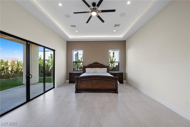 bedroom featuring ceiling fan, access to exterior, multiple windows, and a tray ceiling