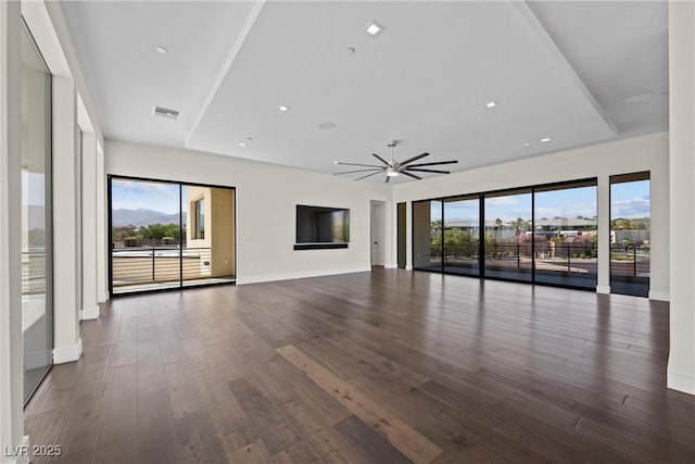 unfurnished living room with ceiling fan, dark hardwood / wood-style flooring, and a raised ceiling