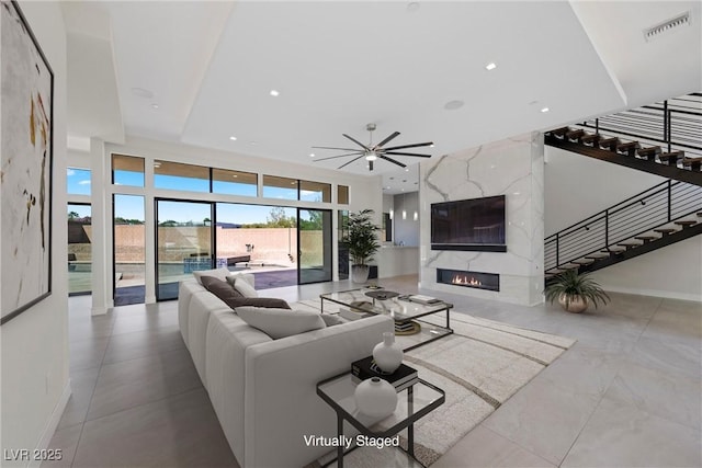 living room featuring ceiling fan and a high end fireplace