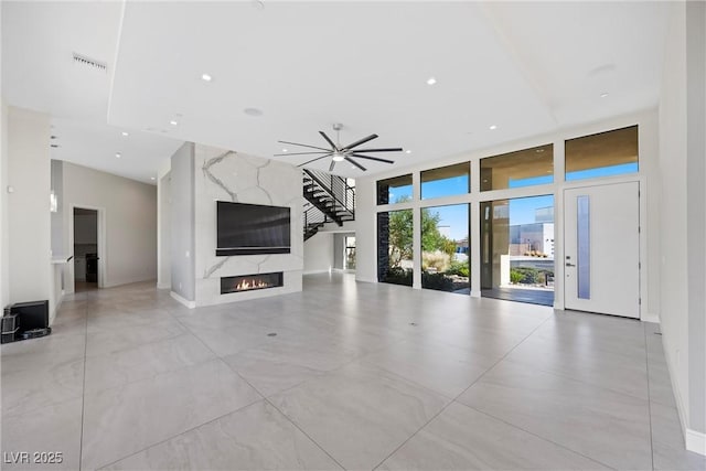 unfurnished living room with ceiling fan and a high end fireplace