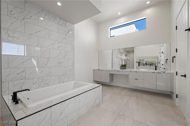 bathroom with tiled tub and vanity