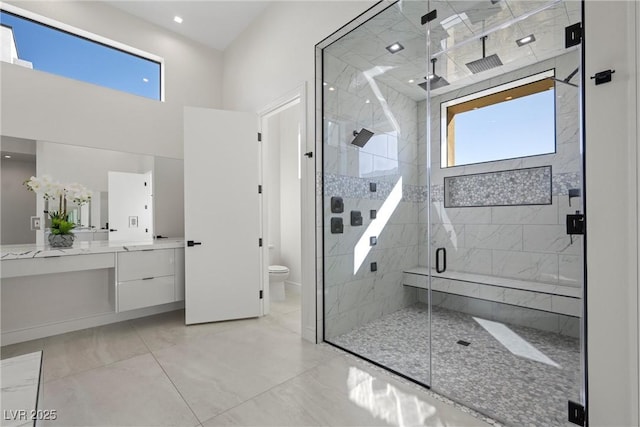 bathroom featuring a shower with shower door, a healthy amount of sunlight, vanity, and toilet