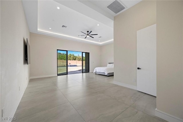 unfurnished bedroom with access to exterior and a tray ceiling