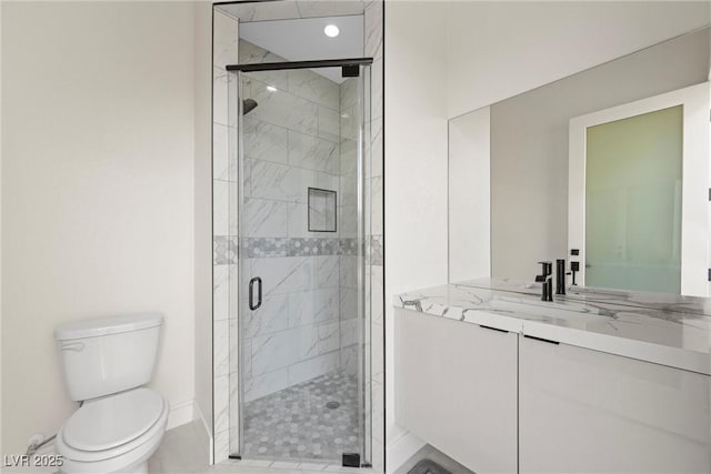 bathroom featuring toilet, a shower with shower door, and vanity