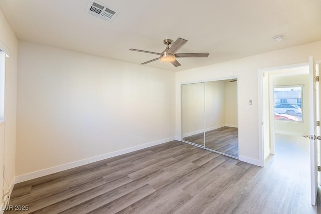 unfurnished bedroom with light wood-type flooring, ceiling fan, and a closet