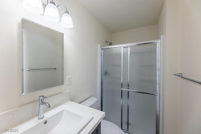 bathroom featuring toilet, a shower with shower door, and vanity