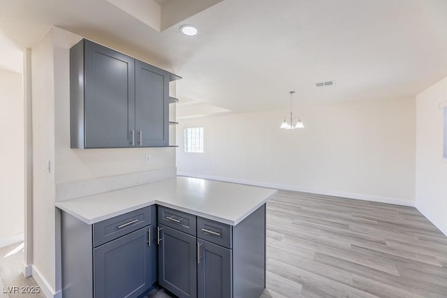 kitchen with light hardwood / wood-style floors, hanging light fixtures, kitchen peninsula, and a notable chandelier