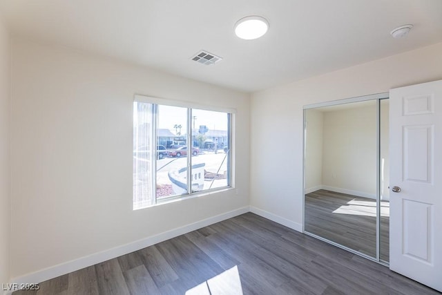 unfurnished bedroom with a closet and dark hardwood / wood-style floors