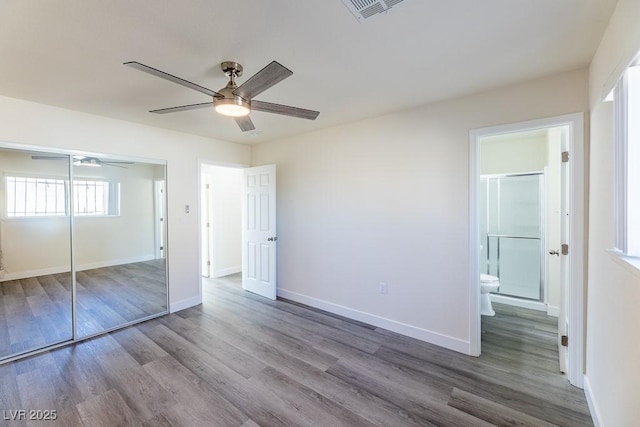 unfurnished bedroom featuring a closet, connected bathroom, hardwood / wood-style floors, and ceiling fan