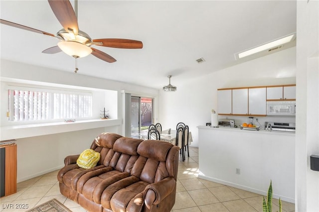 living room featuring ceiling fan, light tile patterned floors, and vaulted ceiling